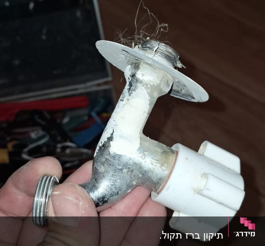 ברז מתכת עם ידית פלסטיק מוחזק ביד